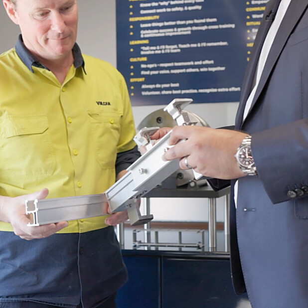 Vulcan's General and Production Manager holding the prototype of low carbon mounting rail